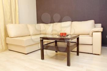 Modern comfortable white leather corner sofa with coffee table.