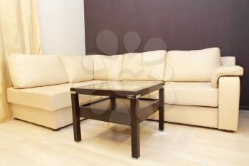 Modern comfortable white corner leather sofa with coffee table.