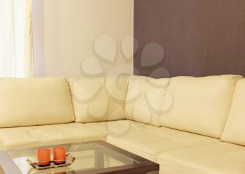 Modern comfortable white leather corner sofa and coffee table taken closeup.