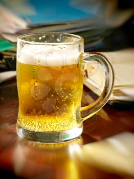 Lunch break-time.Beer glass on table with notebooks.Soft bokeh.