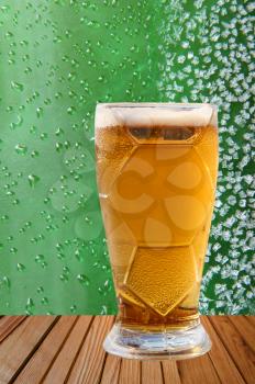 Frost beer glass against of ice crystals and drips green background.