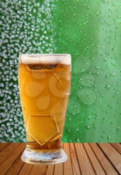 Beer glass taken closeup against of ice crystals and drips green background.