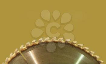 Circular saw blade taken closeup on taupe background with empty space for text.