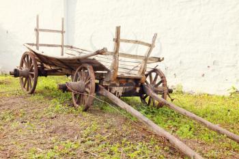 Vintage old rough wooden cart in front of old clay wall.Toned image.