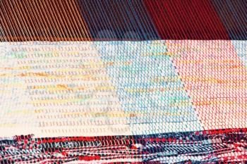 Multicolored rug weaving on a loom taken closeup.