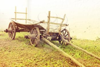 Vintage old rough wooden cart in front of old clay wall.Toned image.