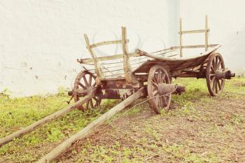 Vintage old rough wooden cart near old clay wall.Toned image.