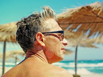 Romantic man face in glasses against of blue sky and sea.Toned image.