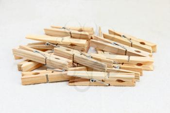 Wooden clothespins heap on white fabric background.