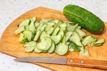 Cucumber and sliced segments on wooden cutting board taken closeup.
