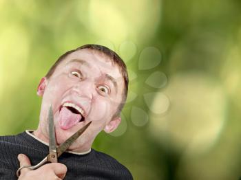 Mad man with scissors cuts off itself tongue on green abstract background.