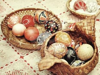 Multicolored easter eggs in straw pots on a table.Retro style toned image.