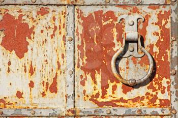 Old rusty metal gate with handle ring taken closeup.
