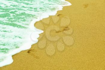Human traces on sandy beach near azure sea surf.