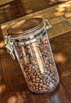Coffee beans in glass container on wooden table.Taken closeup.