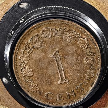 One cent coin taken closeup inside retro camera lens.