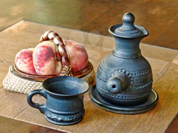 Arabian style coffee pot and peaches in ceramic vase on a table.