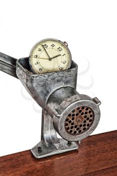 Alarm clock in manual meat grinder on white background.Toned image.