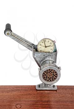 Alarm clock in meat grinder on white background.Toned image.
