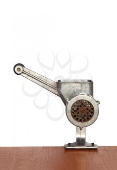 Old manual meat mincer on wooden table and white background.
