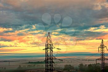Two electricity pylons against of dramatic sunset sky taken closeup.