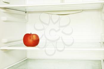 Red single apple in domestic refrigerator taken closeup. Toned image.