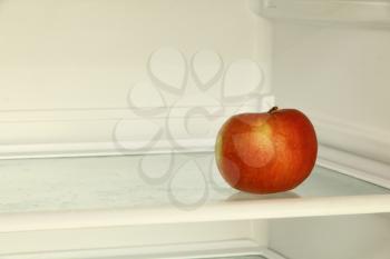 Ripe red apple in domestic refrigerator. Toned image.