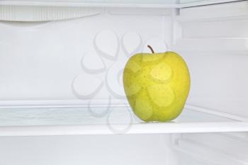 Lifestyle concept.Ripe yellow apple in domestic refrigerator taken closeup.