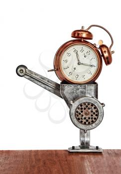 Bronze vintage alarm clock in meat grinder.Toned image.