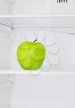 Lifestyle concept.Big green apple in domestic refrigerator taken closeup.Toned image.