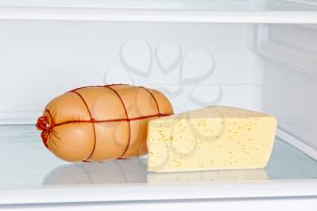 Appetizing sausage and cheese on refrigerator shelf taken closeup.