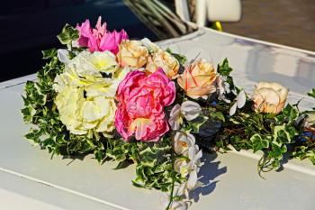 Decorative flowers bouquet on white wedding car taken closeup.