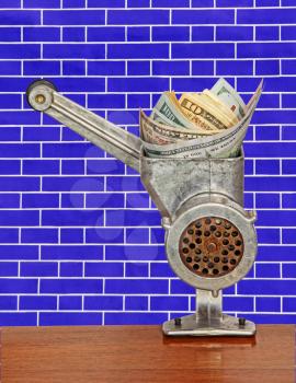 Money Concept.Dollar banknotes in meat grinder on blue brick wall background.