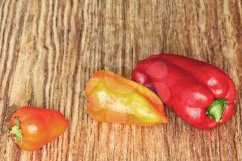 Three sweet peppers on brown wooden background taken closeup.Toned image.