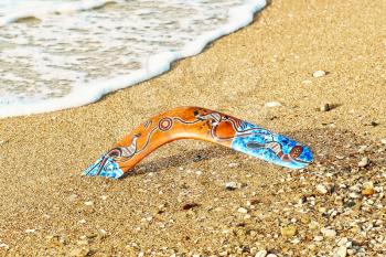 Colorful boomerang on sandy beach near sea surf.Toned image.