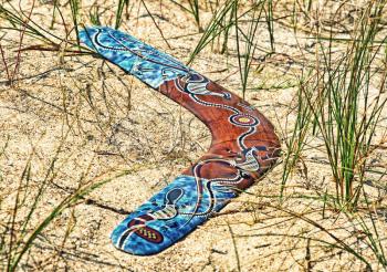 Color Boomerang on sand among a grass taken closeup.Toned image.