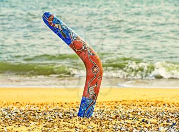 Colorful boomerang on sandy beach against sea surf.Toned image.