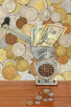Money and business concept.Dollar banknotes in meat grinder and coins on table on lot of different coins background.