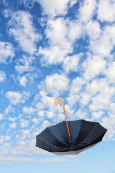Overturn Black Umbrella flies in sky against of pure white clouds.Mary Poppins Umbrella.