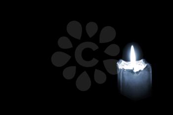 Glowing mourning candle on black background with empty space for text.