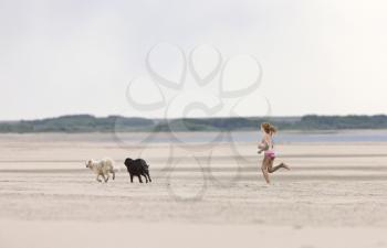 Girl and dogs running along lake shore