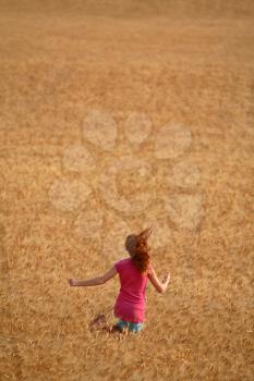 Redhead girl running through a Saskatchewan wheat field