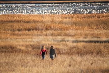 Two girls walking towards snow geese at Nicolle Flats
