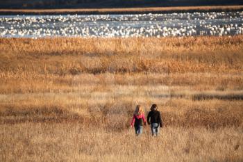 Two girls walking towards snow geese at Nicolle Flats
