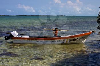 a man and his white boat in the lagoon of sian kaan mexico