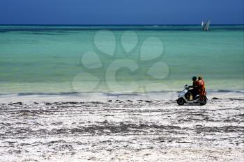 two person in a scooter in the beach of zanzibar