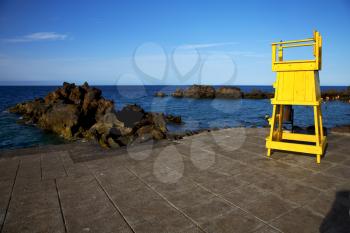 yellow lifeguard chair cabin  in lanzarote  spain   rock stone sky cloud beach  water  musk pond  coastline and summer 
