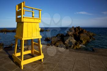 yellow lifeguard chair cabin  in spain  lanzarote  rock stone sky cloud beach  water  musk pond  coastline and summer 
