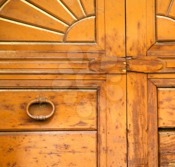 abstract cross   brass brown knocker in a   closed wood door venegono  varese italy