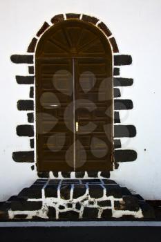 brass brown knocker in a brown closed wood  door and white wall lanzarote abstract  spain canarias
